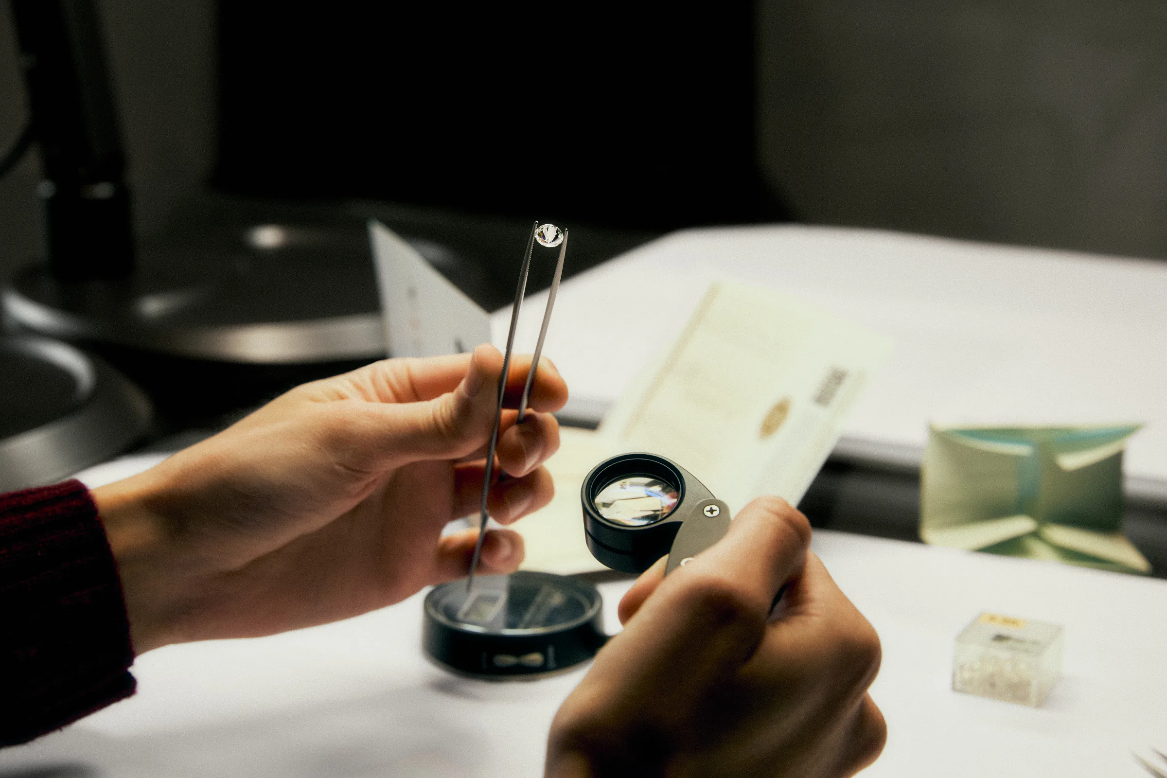 Un joyero examina una piedra con pinzas y lupa sobre la mesa del taller.